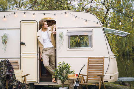 Young stylish american guy,man traveling in camper,house on wheels,trailer,motor home. Romantic road travel,freedom life. Campsite overnight in van. Wanderlust vacation, weekend. happy adventure.の写真素材
