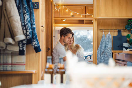 Young just married couple traveling in camper,house on wheels,trailer,motor home.Love romantic road travel,freedom life. Small bed,bedroom in van.Wanderlust vacation,weekend. Girl,guy,happy adventure.の写真素材