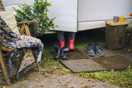 Woman in rubber boots at camper,house on wheels,trailer,motor home. Family traveling, romantic road travel,freedom life.Campsite overnight, parking in van.Wanderlust vacation,weekend. happy adventure.の写真素材