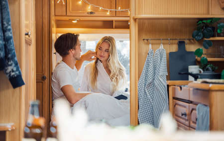 Young just married couple traveling in camper,house on wheels,trailer,motor home.Love romantic road travel,freedom life. Small bed,bedroom in van.Wanderlust vacation,weekend. Girl,guy,happy adventure.の写真素材