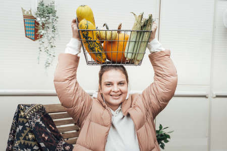 Woman with basket of autumn vegetables. Harvest in garden, farm. Ripe orange pumpkins, squash, ear of corn, zucchini. Healthy organic vegetarian food.の写真素材