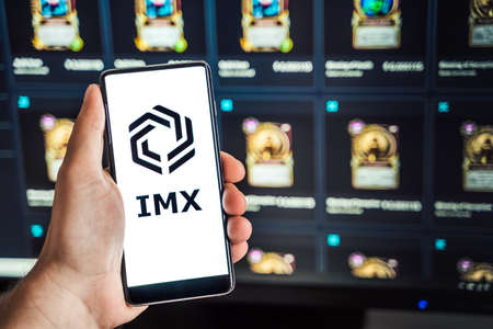 Russia Moscow 04.09.2021.Logo,screenshot of Immutable X, IMX token.Blockchain nft ethereum cryptocurrency game in laptop,mobile phone.Man playing with crypto coins.Earning digital money.Land,heroes.のeditorial素材