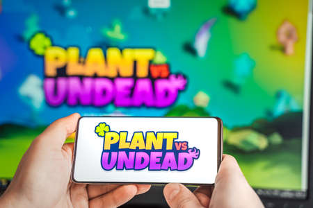Russia Moscow 04.09.2021.Logo,screenshot of Plant vs Undead, PVU token.Blockchain nft ethereum cryptocurrency game in laptop,mobile phone.Man playing with crypto coins.Earning digital money.Land,hero.のeditorial素材