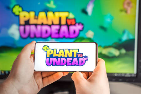 Russia Moscow 04.09.2021.Logo,screenshot of Plant vs Undead, PVU token.Blockchain nft ethereum cryptocurrency game in laptop,mobile phone.Man playing with crypto coins.Earning digital money.Land,hero.のeditorial素材