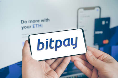 Russia Moscow 19.01.2022 Logo of Bitpay cryptocurrency wallet. Businessman with mobile phone,...