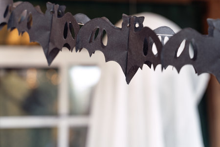 Black paper cut out garland in shape of flying bats.Burning lantern.Decorating of porch outdoor on street for halloween holiday.DIY home,street decoration,entertainment for children,horror atmosphere.の写真素材