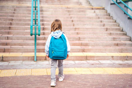 Back to elementary, primary school. Little girl with big backpack goes in hurry, late to first grade alone in autumn morning. Education, future of children. Happy, unhappy pupil kid on stair steps.の写真素材
