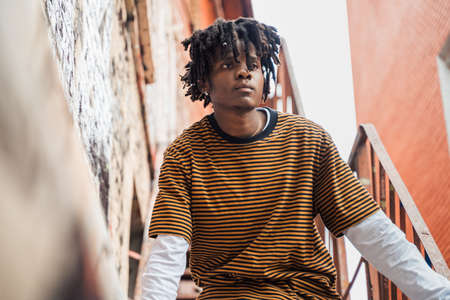 Young stylish handsome black man with natural hair dreadlocks. Afroamerican guy.Stairs,wall painted...