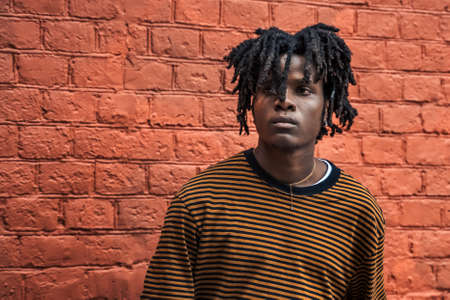 Young stylish handsome black man with natural hair dreadlocks. Afroamerican guy.Stairs,wall painted with graffiti in poor quarter of street art culture city district.African american skateboarder man.の写真素材