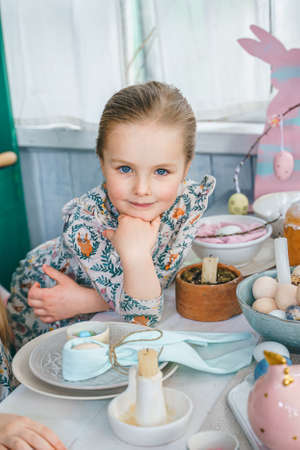 Girl at table with Easter decoration. Celebration in kitchen.Tablescape for home Easter...