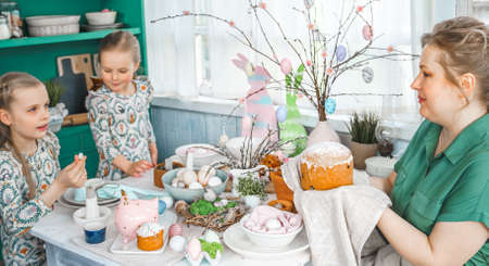 Girls, sisters, mother at table with Easter decoration. Celebration in kitchen.Tablescape for home...