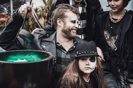 Scary family, mother, father, daughters celebrating halloween. Cauldron of potion.Terrifying black...