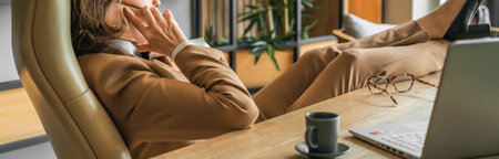 Confident stylish mature middle aged elderly woman in office.Workplace with laptop,using talking by mobile phone.General manager,ceo.Old senior businesswoman,60s lady in suit.Bank entrepreneurial career.の写真素材