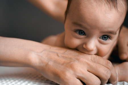 Mom, mummy, young mother with little baby daughter. Mum kissing and hugging child. Newborn cute happy girl smiling in woman hands. Happiness for parents in family. Aged parents, parenting, motherhood.の写真素材