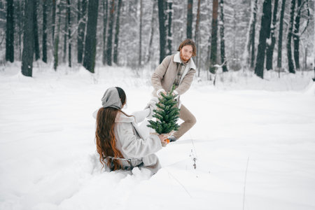 Sledging love romantic young couple girl,guy in snowy winter forest with christmas tree, sled.Walking with sleigh in stylish clothes,fur coat,jacket,woolen shawl.Snow lovestory.Romantic date,weekend.の写真素材