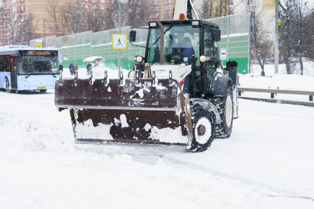 Russia Moscow 13.02.2021 Tractor, snow removal equipment. Street cleaning snow from road, sidewalk. City winter collapse, snowfall, snowdrifts. Heavy snowstorm, blizzard. Weather monthly precipitation.のeditorial素材