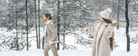 Love romantic young couple girl,guy in snowy winter forest sledding,playing snowballs.Walking with sleigh in stylish clothes, fur coat,jacket, woolen shawl,bonnet.Snow love story.Romantic date,weekend.の写真素材