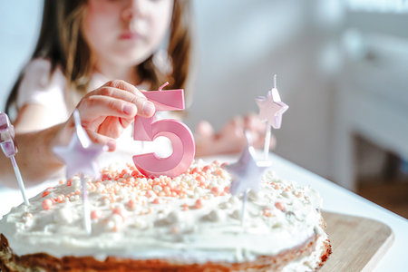 Big pink 5 number candle on homemade cake. Creative congratulations on five years for child girl. Festive decoration for 5th birthday, topping, dressing. Merry home holiday, party with mom, family.の写真素材