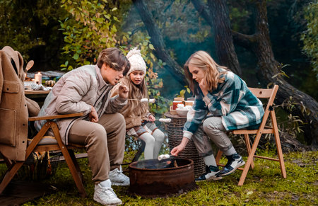 Children,family,brother sister fry marshmallows on fire. Picnic in nature. Wooden...