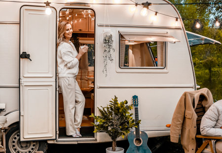 Family trailer travel. Beautiful mom in cozy knitted sweater with cup of tea,coffee.Picnic in...