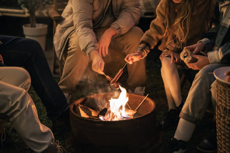 Family trailer travel. Children, brother sister, mom dad fry sausages on fire, eat hot dogs. Evening picnic in nature.Holiday barbecue BBQ food.Vacation weekend dinner.Road lunch.Camper,house on wheels.の写真素材