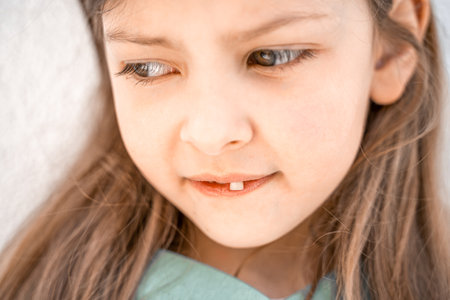 Charming smiling little girl kid with opened mouth shows staggering loose falling out first baby milk front tooth. Preschooler teeth changing. Healthy dental hygiene. lost tooth. Dentist treatment.の写真素材
