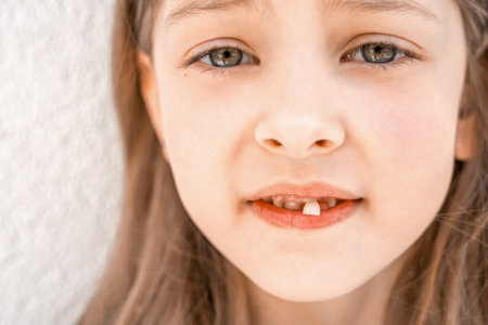 Charming smiling little girl kid with opened mouth shows staggering loose falling out first baby milk front tooth. Preschooler teeth changing. Healthy dental hygiene. lost tooth. Dentist treatment.の写真素材