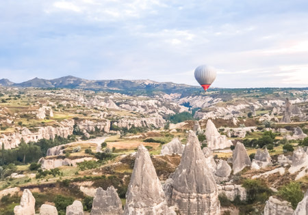 Flying in the sky many bright colored beautiful balloons into the air in Cappadocia in the mountains early at sunrise, dawn. Filling balloon with hot air from burner, big basket. Tourists excursion, cloud flight.の写真素材