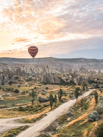 Flying in the sky many bright colored beautiful balloons into the air in Cappadocia in the mountains early at sunrise, dawn. Filling balloon with hot air from burner, big basket. Tourists excursion, cloud flight.の写真素材