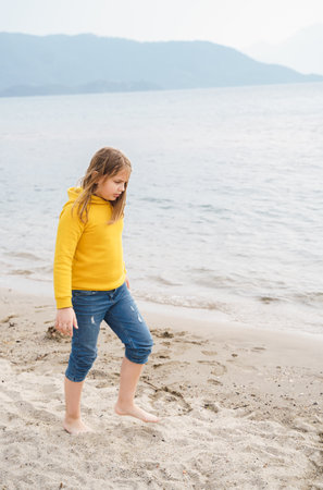 Lonely beautiful sad girl teenager sits thoughtfully on sand sea beach. Dreams, anxiety, worries about the future, school friends, parents. Teen bullying, psychological problems in adolescent puberty period.の写真素材