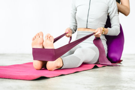Slim woman training with yoga coach. Private lessons with personal trainer, fitness instructor. Workout, exercises at home on fitness mat. Sports equipment, resistance rubber, massage peanut ball.の写真素材