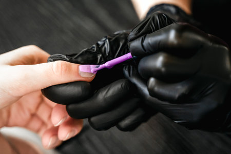 Professional master manicurist at beauty salon. Manicure service, hands treatments, procedures for nails, fingers. Multi-colored nail polish, samples palette, tattoos, cuticle oil, gel uv lamp,gloves.の写真素材