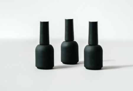 Black bottles with samples of nail polishes on white background. Professional master manicurist at...