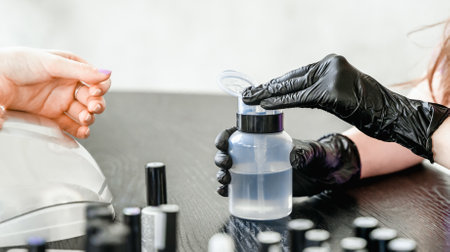 Professional master manicurist at beauty salon. Manicure remove service, hands treatments, procedures for nails, fingers. Multi-colored nail polish remover, sample palette, cuticle oil, gel, uv lamp, gloves.の写真素材