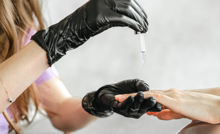 Professional master manicurist at beauty salon. Manicure cuticle oil service, hands treatments, procedures for nails, fingers massage. Multi-colored nail polish, samples palette, gel uv lamp, gloves.の写真素材