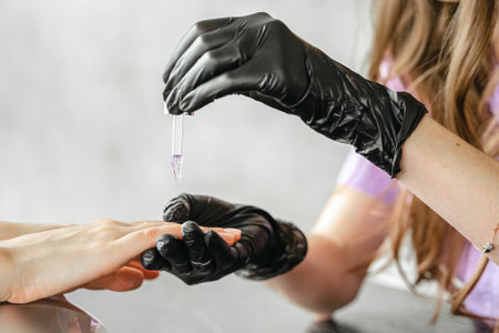 Professional master manicurist at beauty salon. Manicure cuticle oil service, hands treatments, procedures for nails, fingers massage. Multi-colored nail polish, samples palette, gel uv lamp, gloves.の写真素材