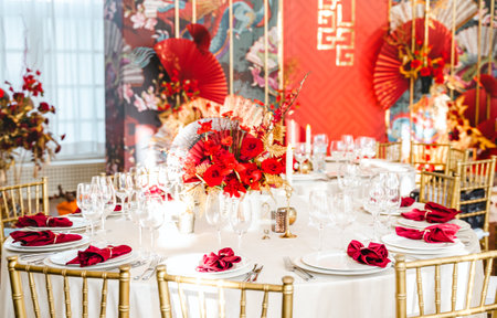 Floral arrangement, festive bouquet, table decoration for Chinese New Year party celebration in restaurant. Traditional red gold color decor. Roses,poppies,fans,candles,tassels. Chinese lunar calendar.の写真素材