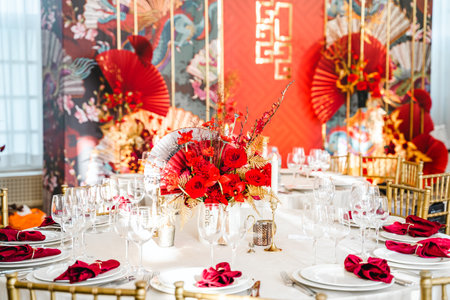 Floral arrangement, festive bouquet, table decoration for Chinese New Year party celebration in restaurant. Traditional red gold color decor. Roses,poppies,fans,candles,tassels. Chinese lunar calendar.の写真素材
