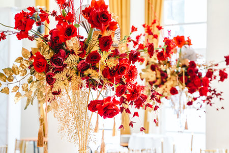 Floral arrangement, festive bouquet, table decoration for Chinese New Year party celebration in restaurant. Traditional red gold color decor. Roses,poppies,fans,candles,tassels. Chinese lunar calendar.の写真素材