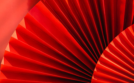 Background with vibrant bright red paper oriental craft fans. Dark texture banner with deep shadows. Chinese New Year celebration. Traditional decor for lunar calendar party.Festive decoration.の写真素材