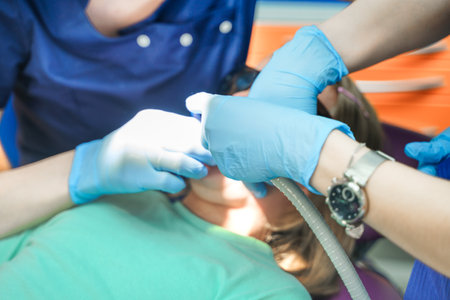 Little scared girl sitting in chair in dentist doctor office. Protective safety sunglasses. Kid,child afraid of tooth extraction, teeth treatment. Open mouth. Dental clinic check-up.Reclined position.の写真素材