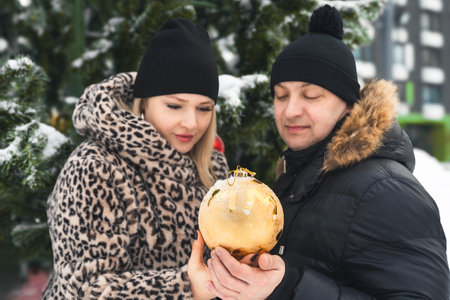 Love romantic couple love story. Man hugging woman, kissing girl in Christmas winter fur trees decoration. Romantic date. Walking, having fun. Stylish clothes, fur leopard print coat, black jacket, hat.の写真素材