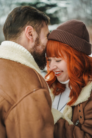 Love romantic couple love story. Brutal bearded man, bright red-haired girl woman in winter park....