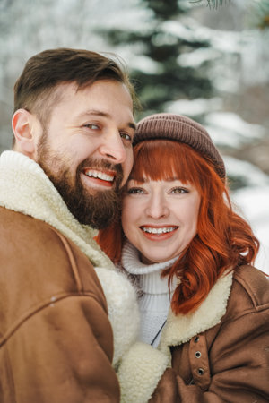 Love romantic couple love story. Brutal bearded man, bright red-haired girl woman in winter park....