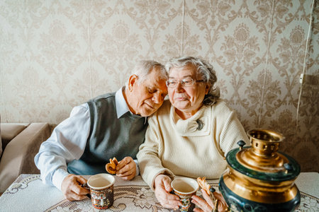 Elderly senior romantic love couple drinking tea with cookies from samovar. Old retired man woman together. Aged husband wife in cozy home. Elder people. Happy family longevity. Tender relationships.の写真素材