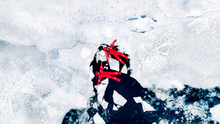 Aerial view of two people ice floating on icy water in bright red survival suits. Arctic frozen landscape. Extreme adventure, ice diving, cold water survival, winter expedition. Fun, outdoor activity.の写真素材