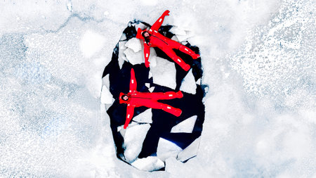 Aerial view of two people ice floating on icy water in bright red survival suits. Arctic frozen landscape. Extreme adventure, ice diving, cold water survival, winter expedition. Fun, outdoor activity.の写真素材