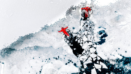 Aerial view of two people ice floating on icy water in bright red survival suits. Arctic frozen landscape. Extreme adventure, ice diving, cold water survival, winter expedition. Fun, outdoor activity.の写真素材