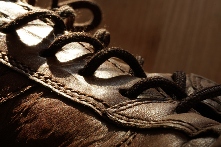 Part of old shoes with laces on wooden floor. Part of old dirty brown leather shoes - space for copy and textの写真素材