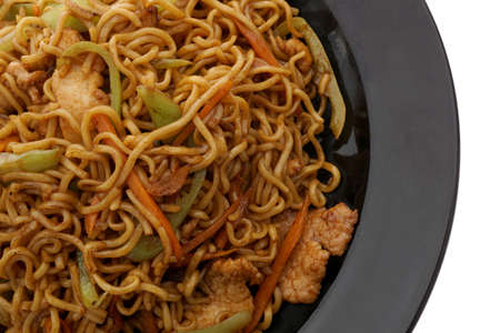 Chinese food. Noodles with pork and vegetables in black plate isolated on white. Closeup.の写真素材